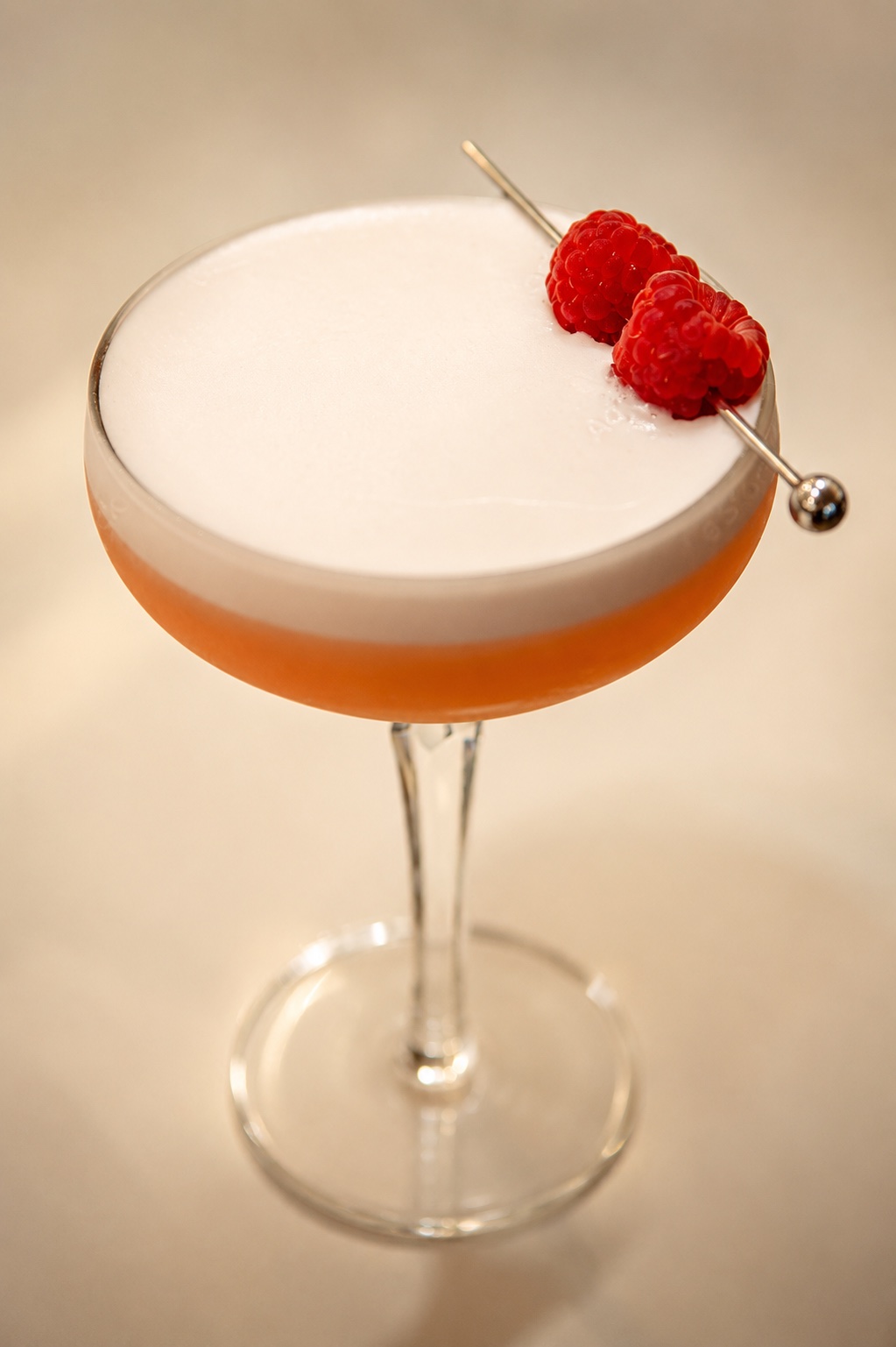 Clover Club cocktail in a coupe with a smooth foam layer and fresh raspberry garnish